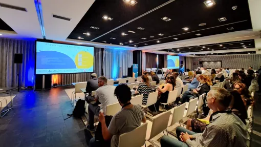 Fotografía sala de congresos con butacas, pantallas de televisión e iluminación azul